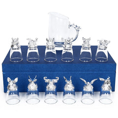 Ensemble complet de 12 verres à shot argentés et de la carafe assortie, disposés sur un coffret cadeau bleu fermé.