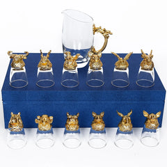 Ensemble complet de 12 verres à shot Luxe à têtes d'animaux dorées et carafe assortie, disposés sur un coffret cadeau bleu fermé.