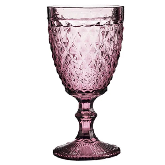 Verre à pied rose dragée à motifs facettés, vu de face sur fond blanc