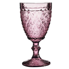 Verre à pied rose dragée à motifs facettés, vu de face sur fond blanc