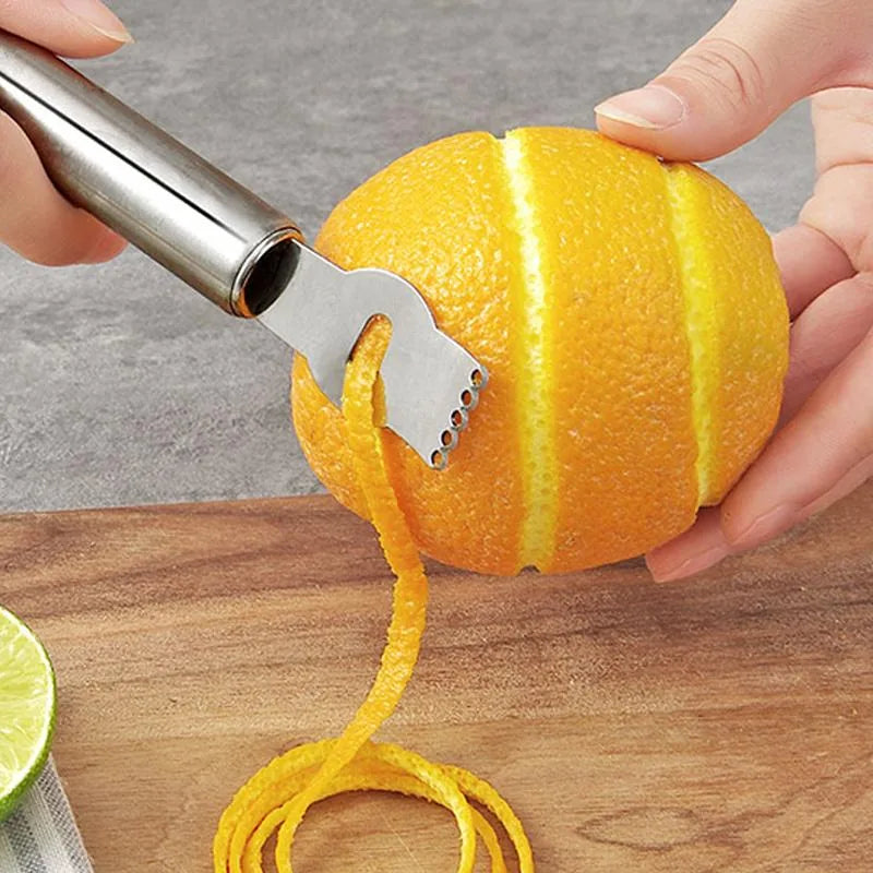Gros plan du zesteur entaillant l'écorce d'une orange pour créer un long zeste continu.