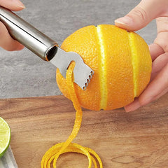 Gros plan du zesteur entaillant l'écorce d'une orange pour créer un long zeste continu.